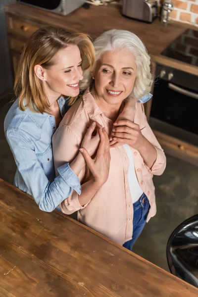 Dos mujeres abrazándose en la cocina - foto de stock