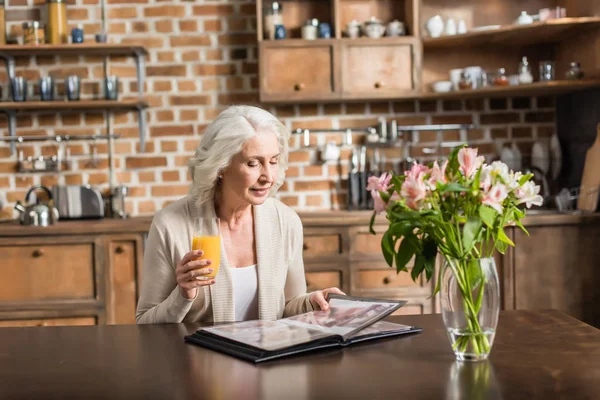 Senior woman looking at photo album — Stock Photo