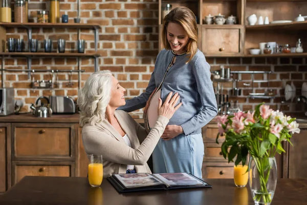Беременная женщина и ее мать на кухне — стоковое фото