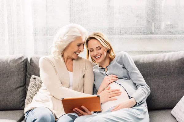 Беременная женщина с матерью на диване — стоковое фото