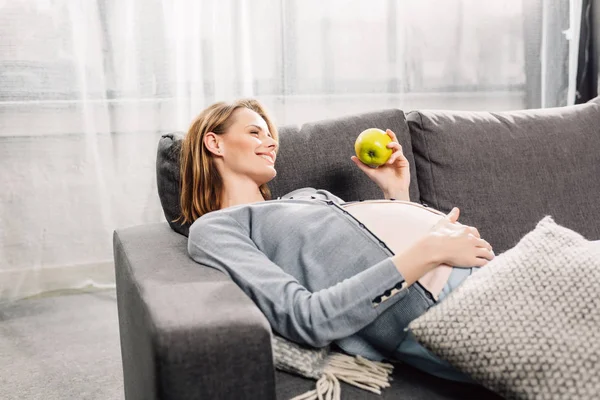 Pregnant woman resting on gray sofa — Stock Photo