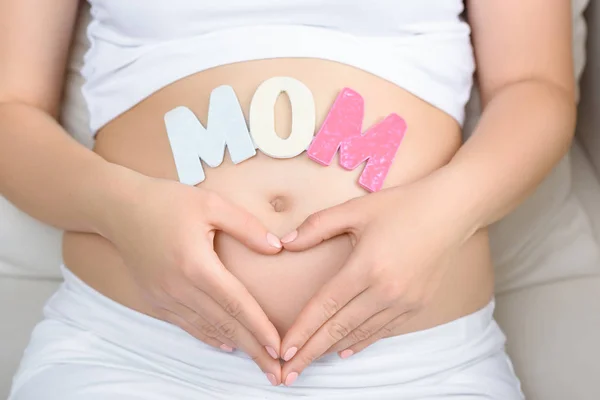 Mujer embarazada con palabra de mamá - foto de stock