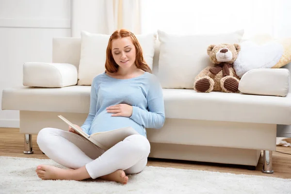 Mujer embarazada lectura libro - foto de stock