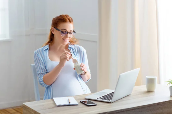 Pregnant woman eating yoghurt — Stock Photo