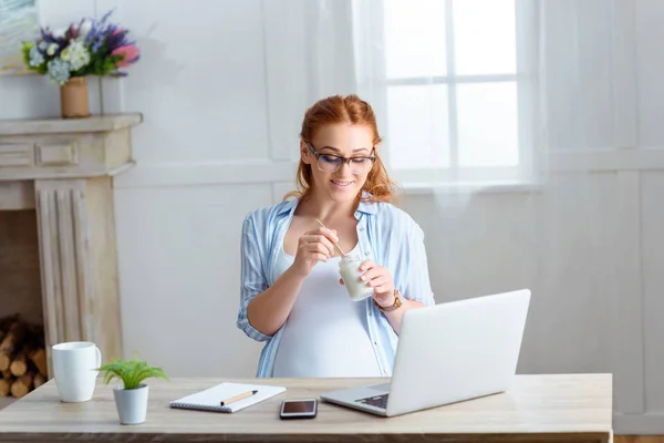 Mujer embarazada comiendo yogur - foto de stock