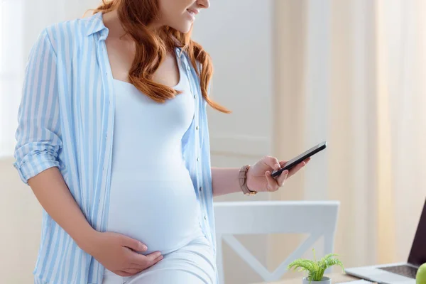 Donna incinta utilizzando smartphone — Foto stock
