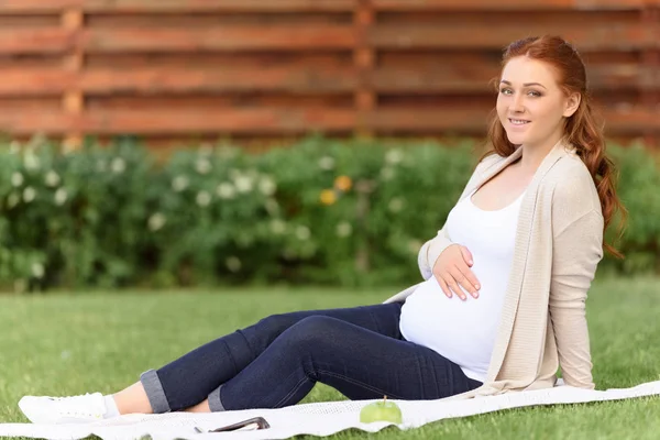 Pregnant woman sitting on lawn — Stock Photo