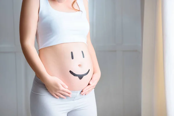 Беременная женщина с символом улыбки — стоковое фото