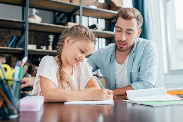 Padre haciendo la tarea con su hija - foto de stock