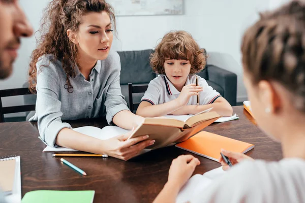 Padres haciendo deberes con niños - foto de stock