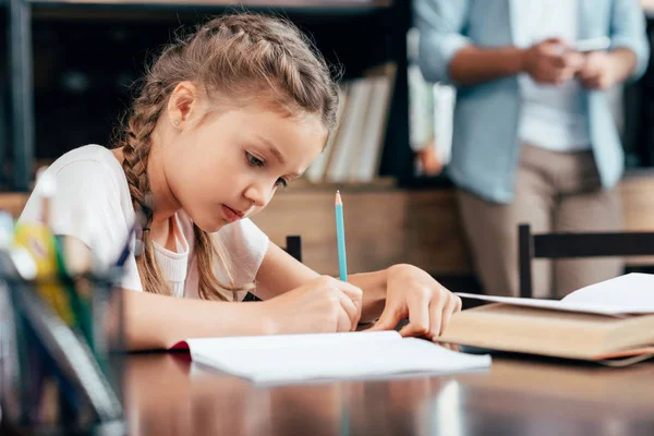 Petite fille écriture devoirs — Photo de stock