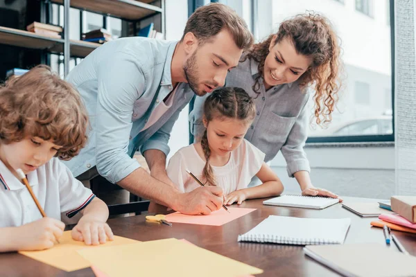 Padres haciendo deberes con niños - foto de stock