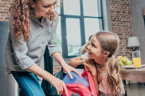 Mère donnant le déjeuner scolaire à sa fille — Photo de stock