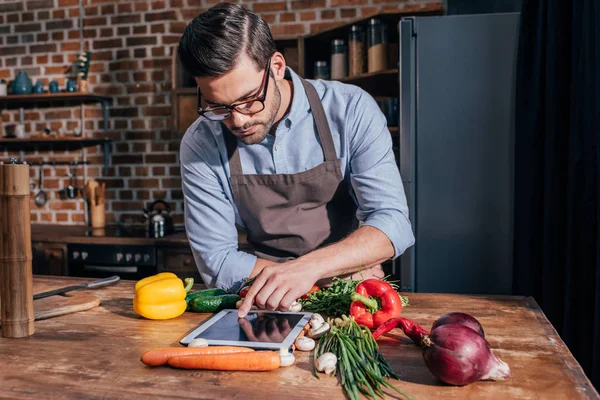 Hombre cocina con la tableta - foto de stock