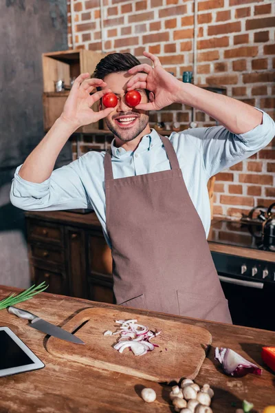 Hombre cubriendo los ojos con tomates - foto de stock