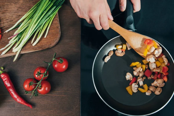 Людина смажить овочі на сковороді — стокове фото