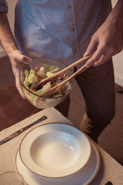 Uomo mettere insalata sul piatto — Foto stock