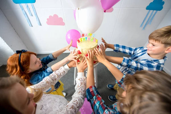 Kids reaching to birthday cake — Stock Photo