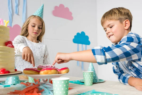 Niño y niña en la mesa de cumpleaños - foto de stock