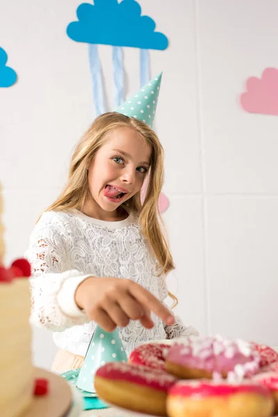 Chica hambrienta señalando donas - foto de stock