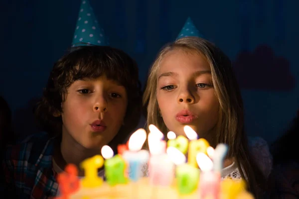 Enfants soufflant des bougies sur gâteau d'anniversaire — Photo de stock