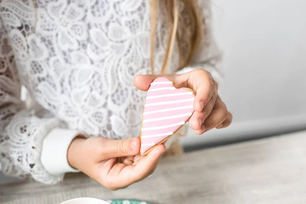 Girl holding heart shaped cookie — Stock Photo