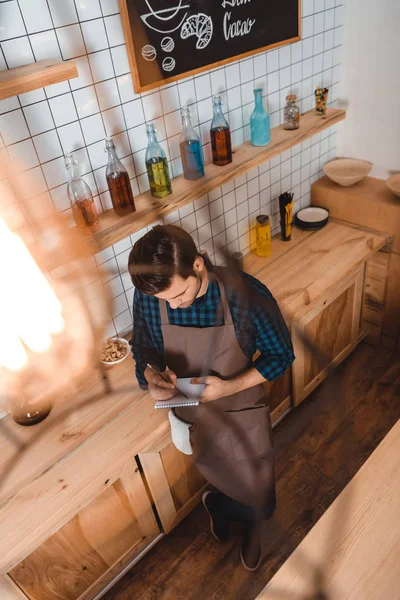 Barista making notes in notebook — Stock Photo