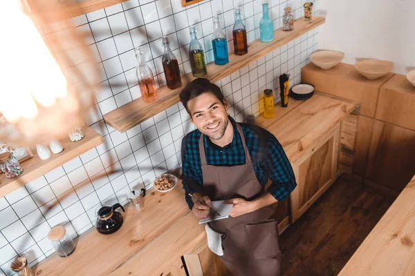 Barista making notes in notebook — Stock Photo