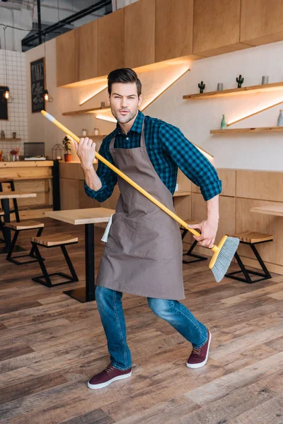 Man having fun with broom in cafe — Stock Photo