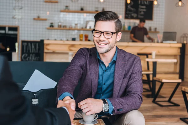 Businessmen shaking hands in cafe — Stock Photo