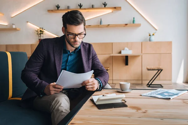Geschäftsmann arbeitet im Café mit Papieren — Stockfoto