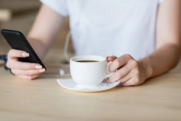 Smartphone y taza de café en manos femeninas - foto de stock
