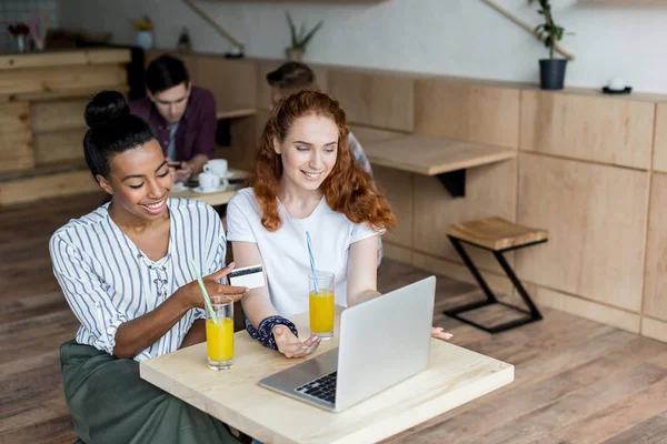 Multiethnic girls with laptop and credit card — Stock Photo