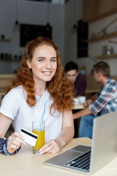 Girl with credit card drinking juice — Stock Photo