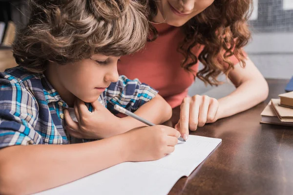 Madre ayudando a hijo con la tarea - foto de stock