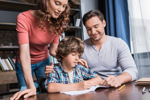 Padres ayudando a su hijo con la tarea - foto de stock