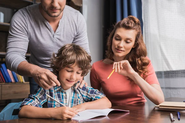 Padres ayudando a su hijo con la tarea - foto de stock