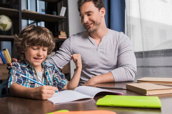 Hijo haciendo la tarea con padre - foto de stock