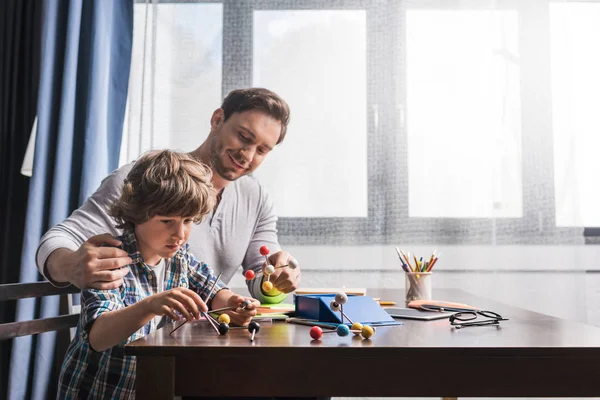 Padre e hijo jugando con el modelo de átomos - foto de stock