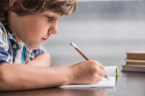 Kid writing in copybook — Stock Photo