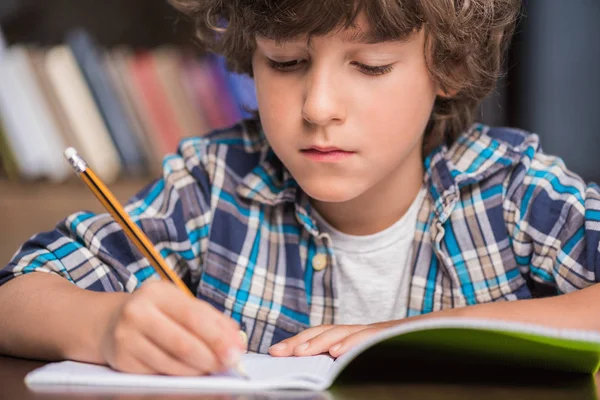 Kid writing in copybook — Stock Photo