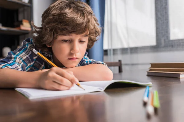 Kid writing in copybook — Stock Photo