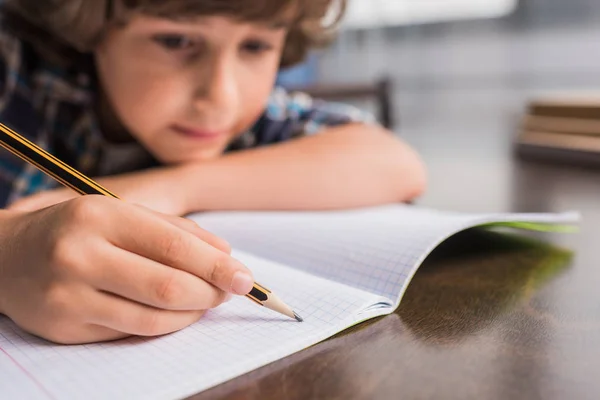 Kid writing in copybook — Stock Photo