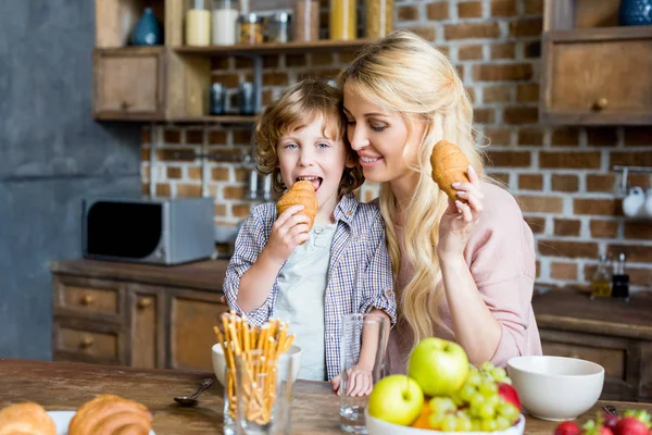 Mãe e filho comendo croissants — Fotografia de Stock
