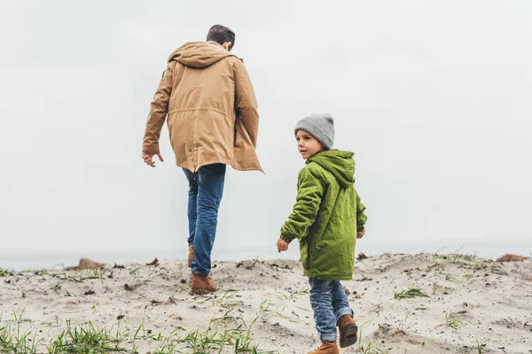 Отец и сын прогуливаются вдоль песчаного пляжа — стоковое фото