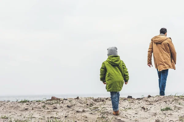 Отец и сын прогуливаются вдоль песчаного пляжа — стоковое фото