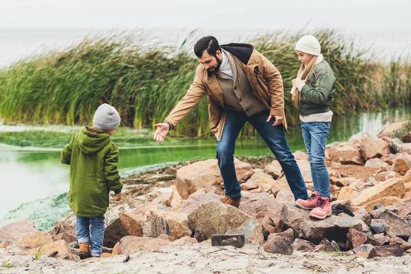 Padre e hijos en la costa rocosa - foto de stock