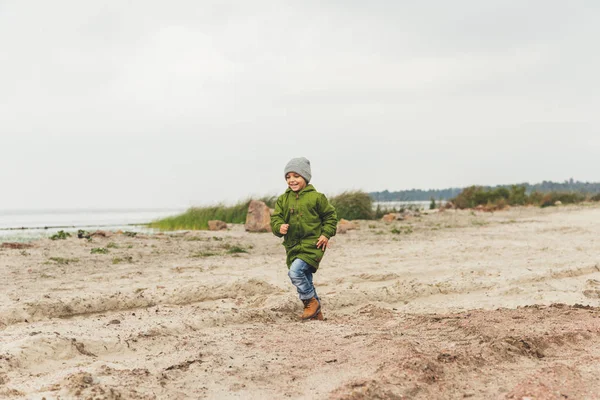 Chico corriendo por la playa de arena - foto de stock