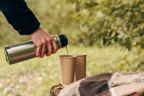 Mann gießt Tee aus Thermoskanne — Stockfoto