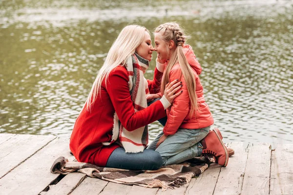 Mother and daughter sitting near lake — Stock Photo
